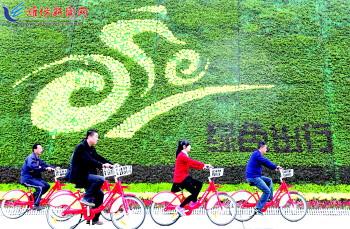 市民騎公共自行車路過(guò)市人民廣場(chǎng)一處花壇。記者 張馳